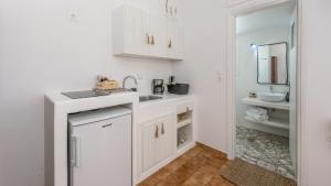 cocina con armarios blancos, lavabo y espejo en Litsa Malli Rooms, en Pollonia