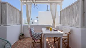 a small balcony with a white table and chairs at Litsa Malli Rooms in Pollonia