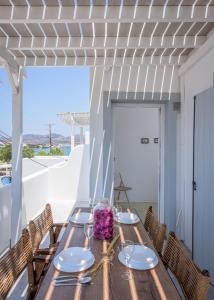 una mesa de madera y sillas en un patio con vistas al océano en Litsa Malli Rooms, en Pollonia