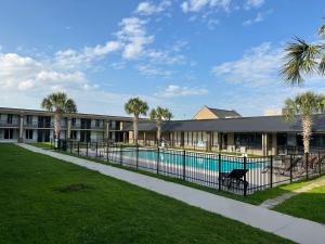 a building with a swimming pool and palm trees at Days Inn & Suites by Wyndham Jennings in Jennings