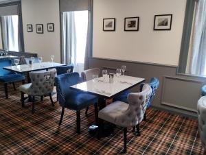 a dining room with two tables and blue chairs at Royal Thurso Hotel in Thurso