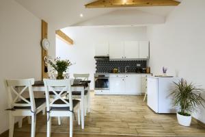 uma cozinha com armários brancos e uma mesa e cadeiras em Apartament Abra 1 Rynek 8 em Muszyna