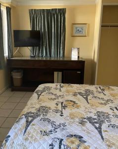 1 dormitorio con 1 cama, TV y escritorio en Ocean Cove Motel en Virginia Beach