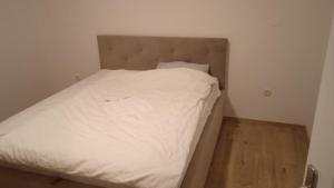 Cama en habitación pequeña con sábanas blancas en MD1, en Trebinje