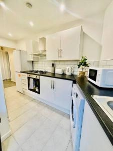 a kitchen with white cabinets and a black counter top at Brand New 2-BR Home Close to the City Centre in Liverpool