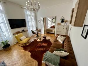 sala de estar con sofá marrón y lámpara de araña en Appartement de charme en plein coeur de Rouen, en Rouen