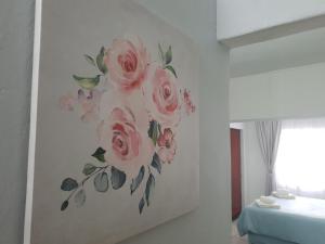 a painting of pink roses on a wall in a bedroom at Tia's Place in Krugersdorp