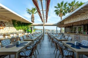 a restaurant with tables and chairs and palm trees at Gumbet Anil Beach in Gümbet