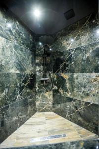 a bathroom with a shower with black marble walls at Le Legendary Spa, hypercentre avec sauna, balnéo et wifi par SOVALFI in Saint-Étienne
