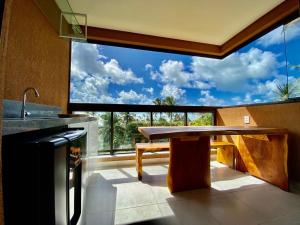 a kitchen with a table and a large window at Flat luxo 04 torre 06 Eco Resort Carneiros in Tamandaré