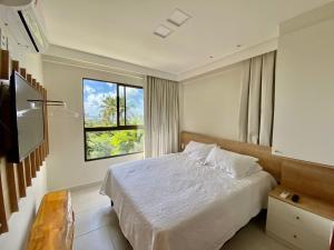 a bedroom with a large bed and a window at Flat luxo 04 torre 06 Eco Resort Carneiros in Tamandaré +41 photos