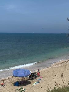 una playa con sombrilla azul y gente en la playa en The Stylish Apt of Mine, en Haifa