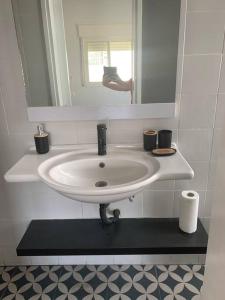 lavabo blanco en el baño con espejo en The Stylish Apt of Mine, en Haifa