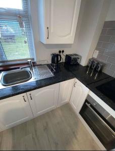 a kitchen with white cabinets and a sink at Avondale Lodge in Sligo