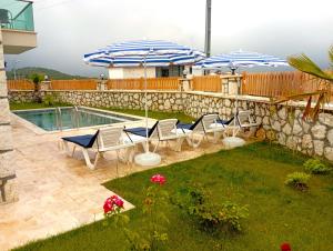 eine Terrasse mit Stühlen und Sonnenschirmen neben einem Pool in der Unterkunft Dreamy Vacation Villa with Pool in Kalkan Antalya in Kalkan
