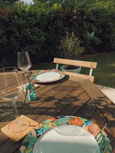a wooden table with a plate and wine glasses at Lea , La Clef du Bonheur - 9 Min de Disney Jardin privatif in Bailly-Romainvilliers