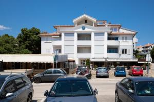 a large white building with cars parked in a parking lot at Pjescana Uvala Sea View Apartment in Pješčana Uvala 