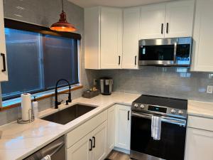 a kitchen with white cabinets and a sink and a microwave at Crescent Bar Waterfront Home- Private Beach, Water Views, Hiking, Golf, Live Concerts in Quincy