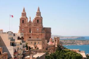 un vieux bâtiment avec deux tours au sommet d'une ville dans l'établissement City Center Apartments, à Mellieħa