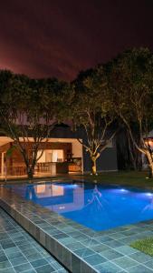 a swimming pool at night with trees in the background at Pousada Noah in Capitólio
