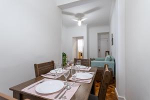 uma sala de jantar com uma mesa de madeira e copos de vinho em Gracioso no Leblon - 2 quartos - AP102 no Rio de Janeiro