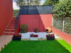 a garden with potted plants and a red wall at URBANIZACION MIRAMAR PENISCOLA in Peniscola