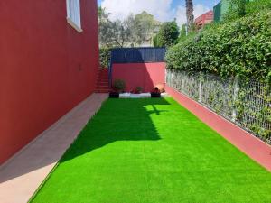 un jardín con césped verde junto a una pared roja en URBANIZACION MIRAMAR PENISCOLA, en Peñíscola