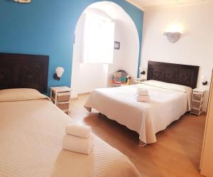 twee bedden in een kamer met blauwe muren en een raam bij Alcamim Guesthouse in Elvas