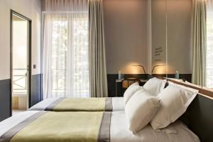 sypialnia z dużym łóżkiem z białymi poduszkami w obiekcie Hôtel Gaston w Paryżu