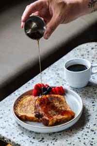 a person pouring syrup on a plate of french toast at Black Llama Hostel Miraflores in Lima