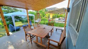een veranda met een houten tafel en stoelen en een parasol bij Cozy villa, Golem beach. in Golem
