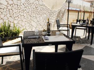 a patio with tables and chairs and a stone wall at Hotel Barbieri in Vibo Valentia Marina