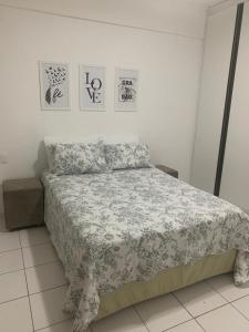 een slaapkamer met een bed met een deken en foto's aan de muur bij Apt no Melhor local em Lauro de Freitas in Lauro de Freitas