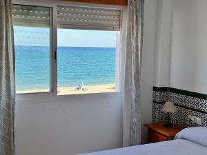a bedroom with a window with a view of the beach at La Vela Playa 1 in Roquetas de Mar