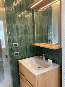 a bathroom with a sink and a green tiled wall at B&B Villa Cortese in Clusone