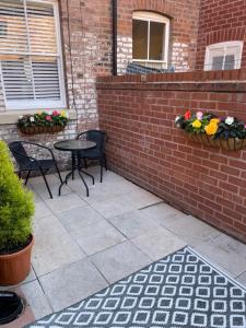 un patio con 2 sillas, una mesa y flores en The Hideaway en Chester