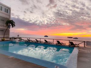 a swimming pool with a view of the ocean at sunset at OEManagement Hotel Rooms in Roseau