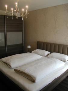 a bedroom with a large bed with white sheets and a chandelier at Lifestyle Beauty & Wellness in Moosbach