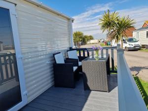 a patio with chairs and a table on a deck at Seaside Holiday Home Inside a Resort in Selsey