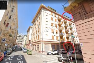 a tall white building on a city street with parked cars at Casa Adry in Genova
