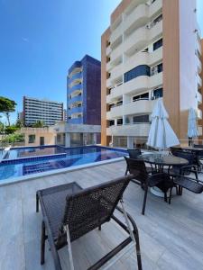 a patio with tables and umbrellas next to a building at Apt no Melhor local em Lauro de Freitas in Lauro de Freitas