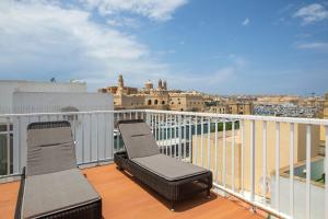 two chairs on a balcony with a view of a city at Traditional & Modern Maltese Townhouse - Rooftop Terrace and Sea Views, close to Birgu Waterfront in Cospicua