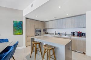 a kitchen with a counter and two stools at The Ultimate Resort - BEACHFRONT 2 BEDROOM APARTMENT WITH DIRECT OCEAN VIEW, ROOFTOP POOL, HOT TUB AND GYM in Hollywood