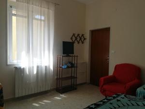 ein Wohnzimmer mit einem roten Stuhl und einem Fenster in der Unterkunft La Dimora di Anna in Praia a Mare