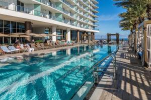 una piscina in un resort con persone sedute su sedie di The Ultimate Resort #2904 - BEACHFRONT 2 BEDROOM APARTMENT WITH DIRECT OCEAN VIEW, ROOFTOP POOL, HOT TUB AND GYM a Hollywood