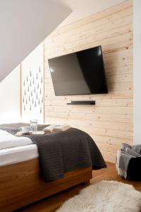 a bedroom with a bed with a flat screen tv on the wall at Mountain Base - Dwupoziomowy apartament "Przy lesie II" z prywatnym jacuzzi w Kościelisku in Kościelisko
