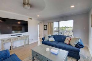 uma sala de estar com um sofá azul e uma mesa em El Matador 539 - Third floor unit em Fort Walton Beach