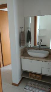 a bathroom with a sink and a mirror at Nautilus Paraíso Tropical - Vista ao Mar in Penha