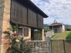 uma casa de pedra com uma cerca e um edifício em LA COROLLA em Villaviciosa