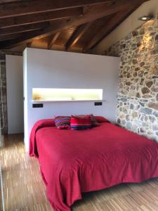 um quarto com uma cama vermelha e uma parede de pedra em LA COROLLA em Villaviciosa